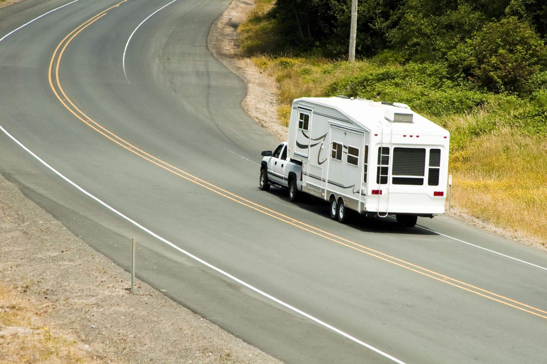 Recreational vehicle towing a trailer along a winding rural road