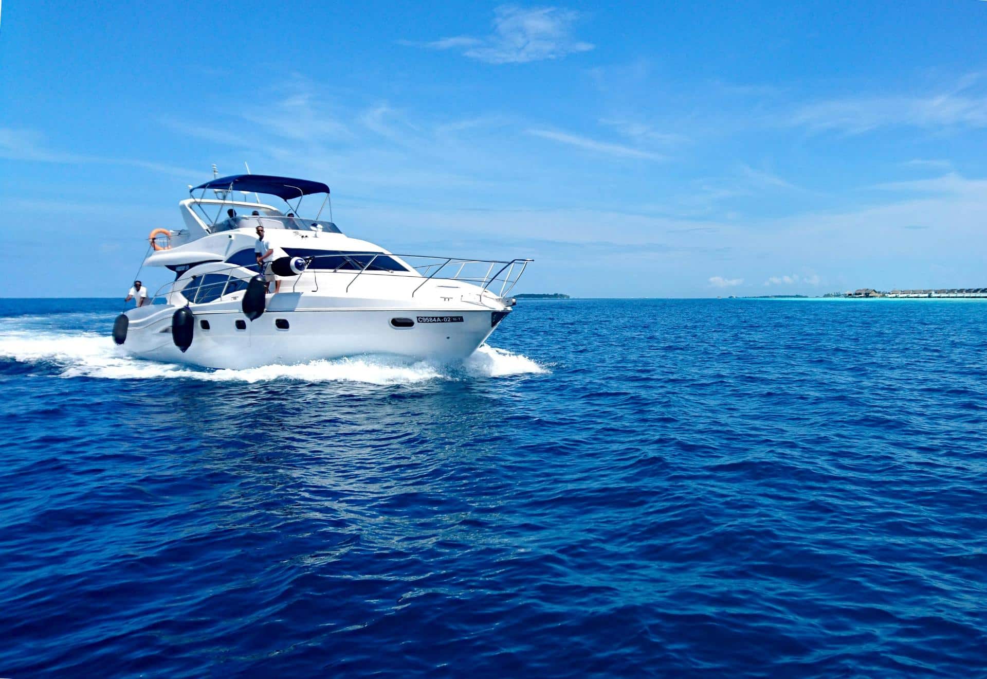 Motor yacht cruising across open blue water near shoreline